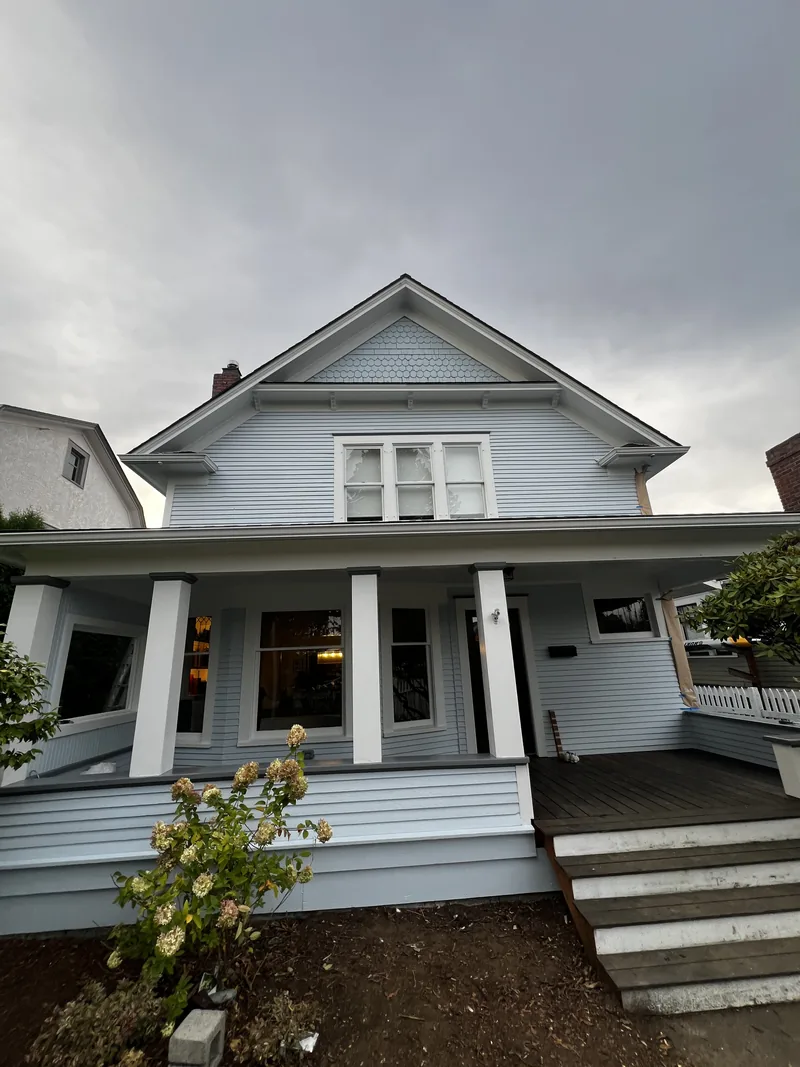 Broadway Park Victorian in Bellingham after exterior painting in soft blue with white trim and restored fish-scale gable shingles.