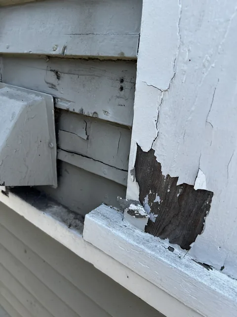 Frieze board worn to bare wood beside a vent, with alligatored paint on the trim of a 1909 Bellingham home.