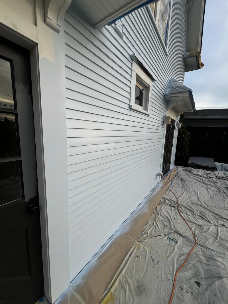 Repaired and repainted lap siding on a Bellingham home with masking still in place.