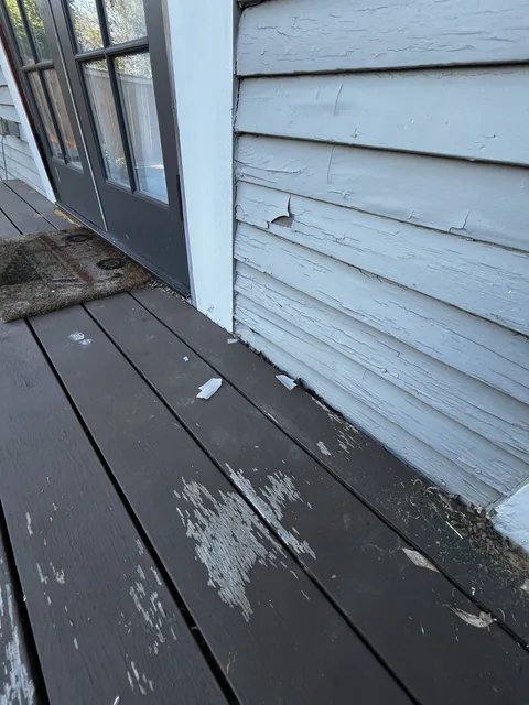 Loose paint chips from failing siding lying on a deck at a pre-1978 Bellingham home.