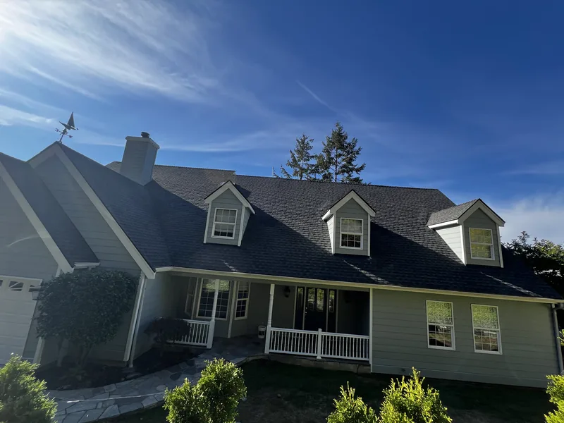 Finished exterior repaint of a home on Chuckanut Drive in Bellingham with dormers and a white porch railing