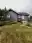 Garden-side view of the finished Eldridge exterior repaint—gray siding and white trim above a landscaped yard with a red railing, Bellingham, WA.