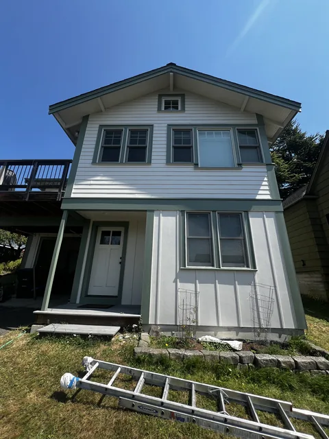 Finished front elevation of a Fairhaven home in Bellingham, WA—lap siding, board-and-batten, and stucco refinished with sage green trim.